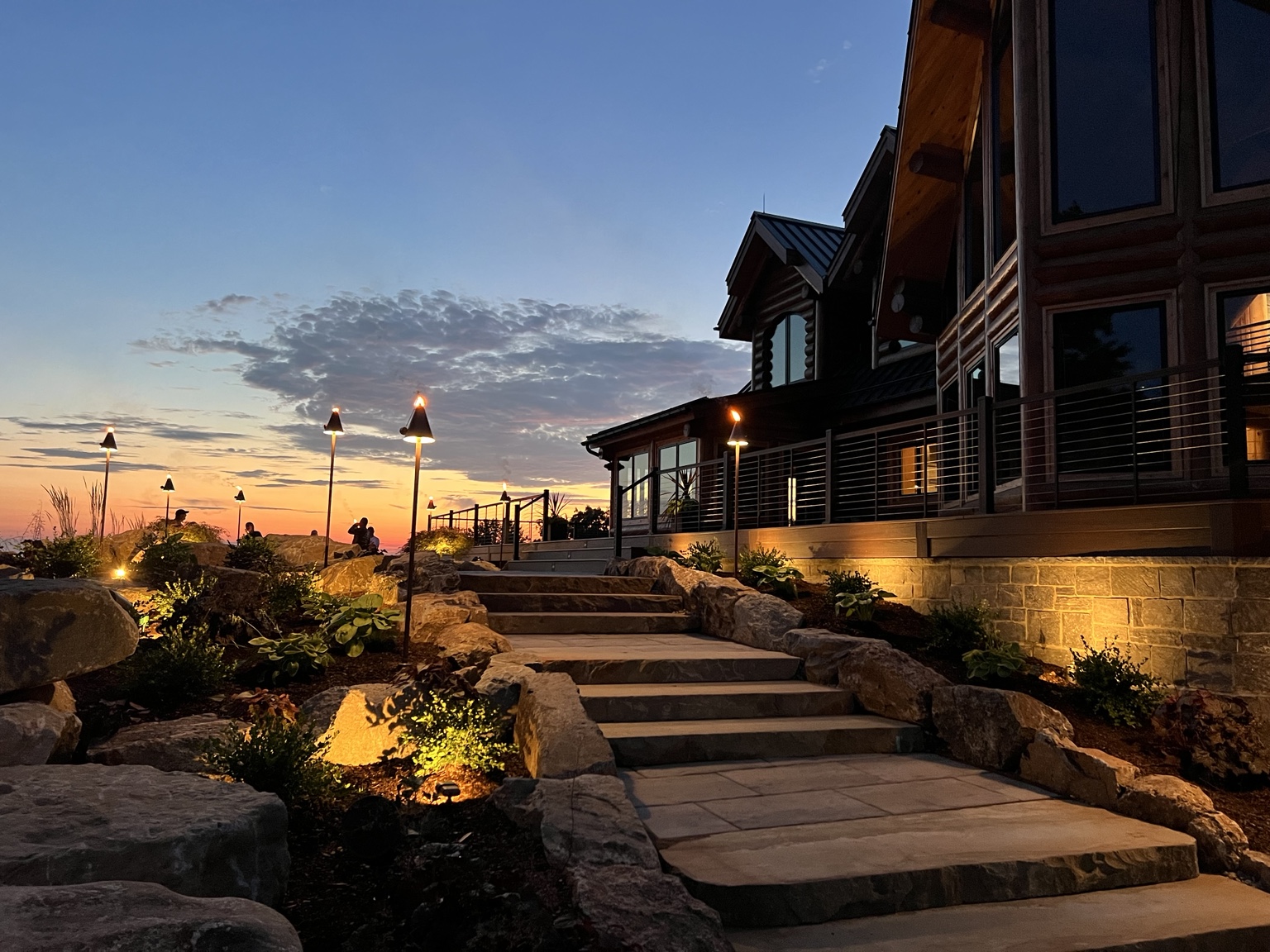 Stone steps, boulders and warm landscape lighting beside a Bucks County home at sunset